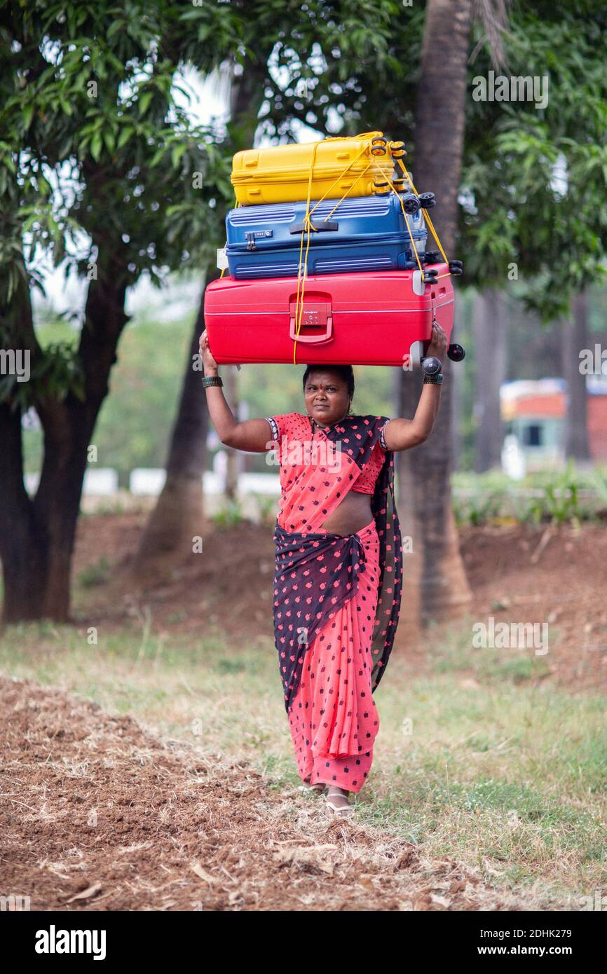 Ländliche indische Frau, die Gepäck auf dem Kopf trägt Stockfoto
