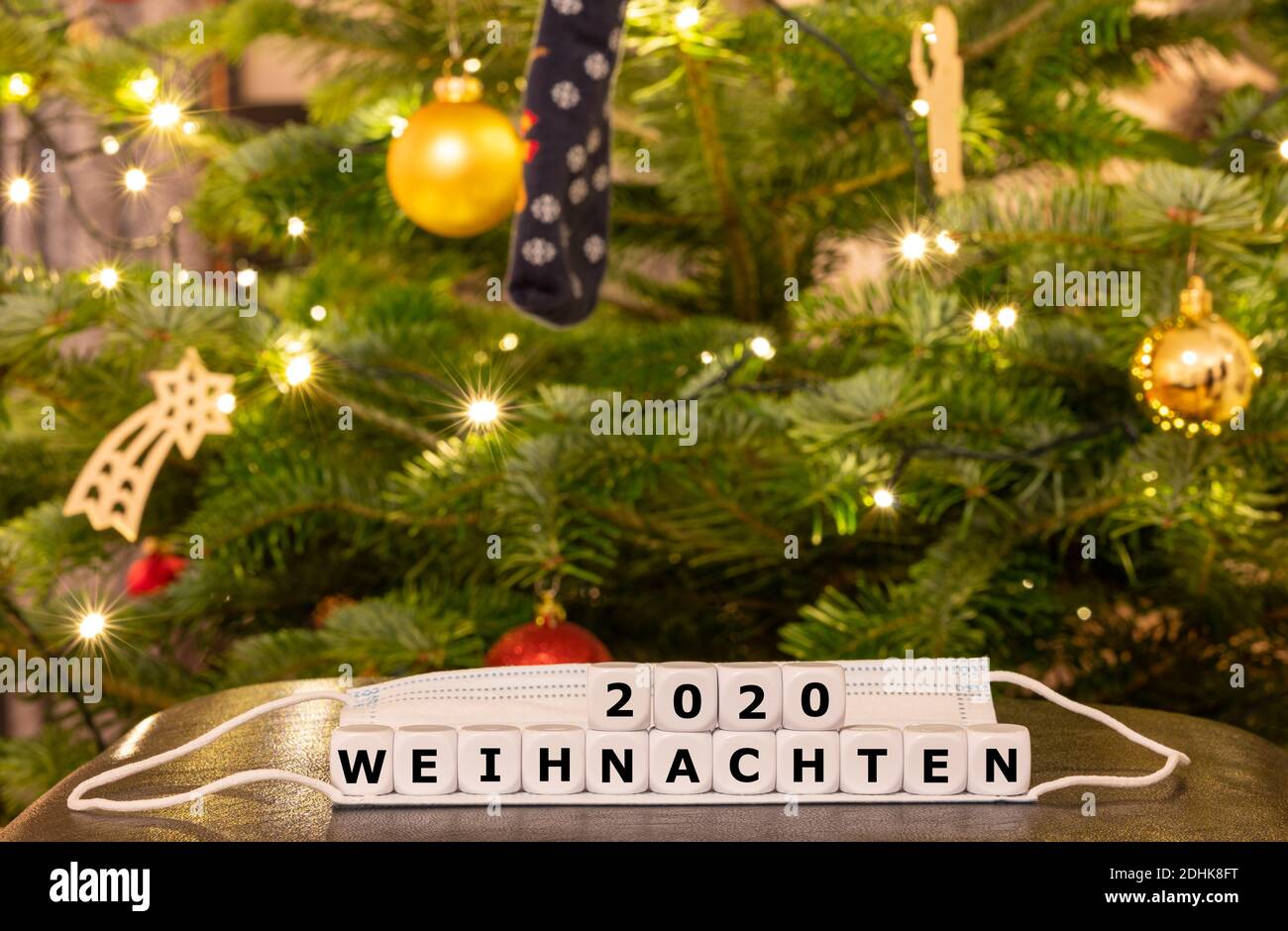 Symbol für die Weihnachtszeit während der Corona-Pandemie. Würfel bilden den deutschen Ausdruck 'Weihnachten 2020' (Weihnachten 2020) auf einer Gesichtsmaske Stockfoto