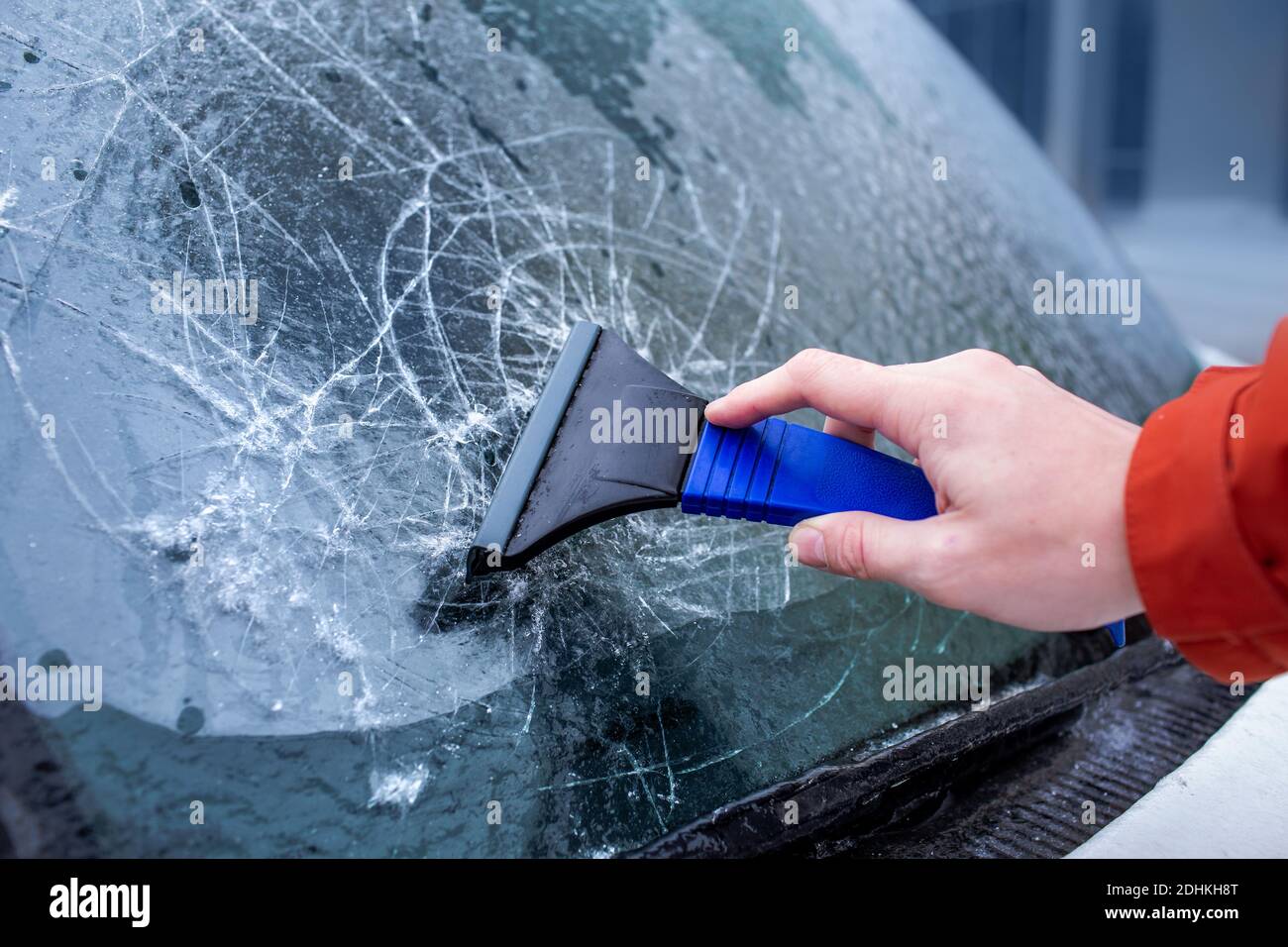 Eis verkrustet auf Autoscheiben. Der Fahrer kratzt Eis von der Windschutzscheibe. Eisiger Regen, Anomalien der Natur Stockfoto