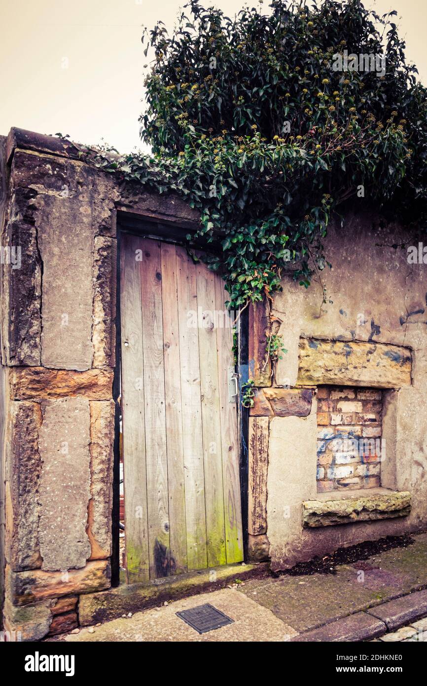 Sonne gebleicht und abgenutzt Hinterhof Tor oder Tür neben einem gemauerten Kohleloch, in Consett, County Durham, Großbritannien Stockfoto