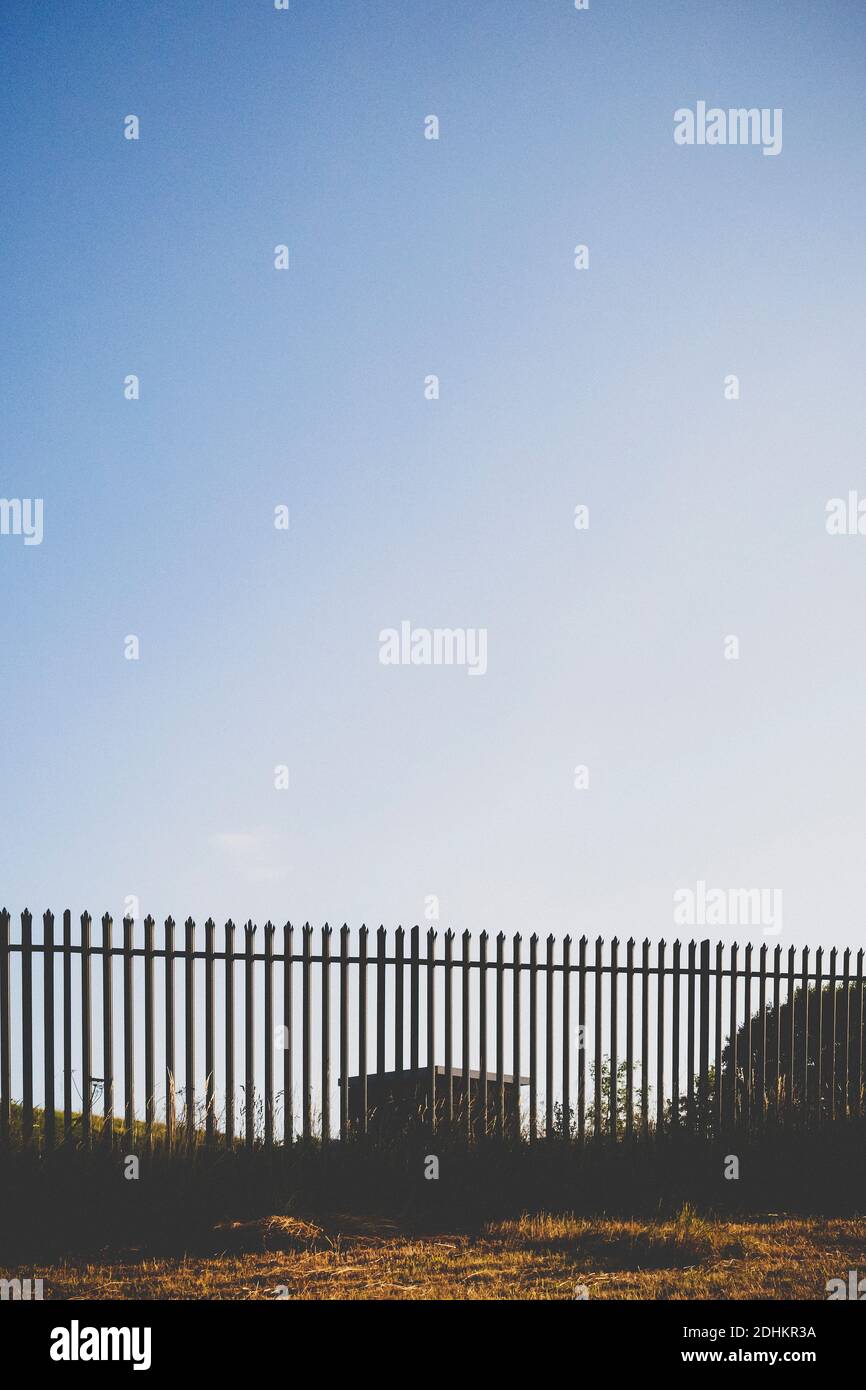 Kleines Ziegelgebäude hinter einem Metallzaun. Stockfoto