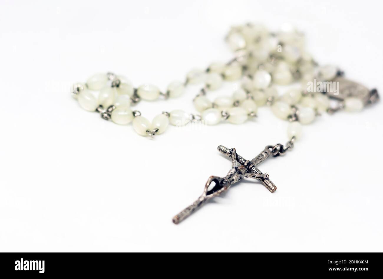 Weißer Perlenrosar mit silbernem Kruzifix isoliert auf weißem Hintergrund. Gebet und Hingabe. Religiöses Objekt. Stockfoto