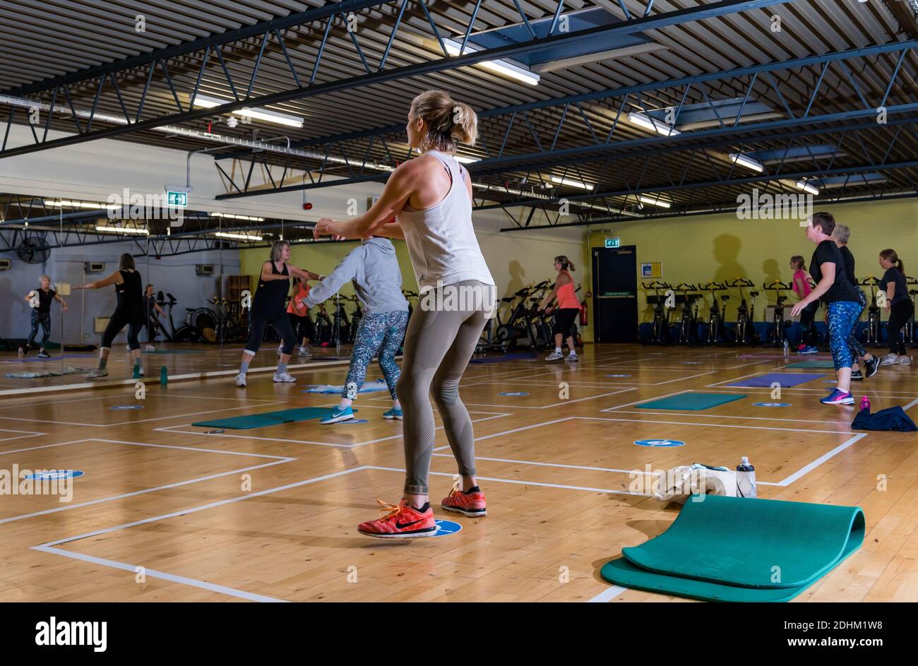 Frauen, die in Übung Workout-Klasse im Fitnessstudio mit sozialen Distanzmarken auf dem Boden trainieren, North Berwick Enjoy Leisure Sports Centre, Schottland, Großbritannien Stockfoto