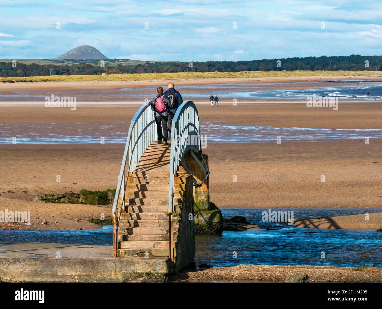 Menschen, die bei Ebbe über Bridge to Nowhere, Belhaven Bay, East Lothian, Schottland, Großbritannien, laufen Stockfoto