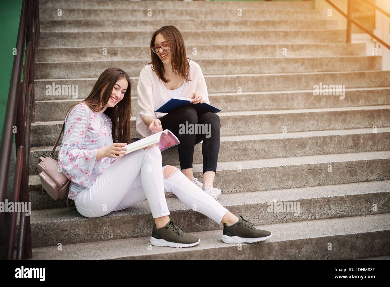 Zwei charmante schöne High School Mädchen sitzen auf Treppen draußen und Hausaufgaben zusammen. Stockfoto