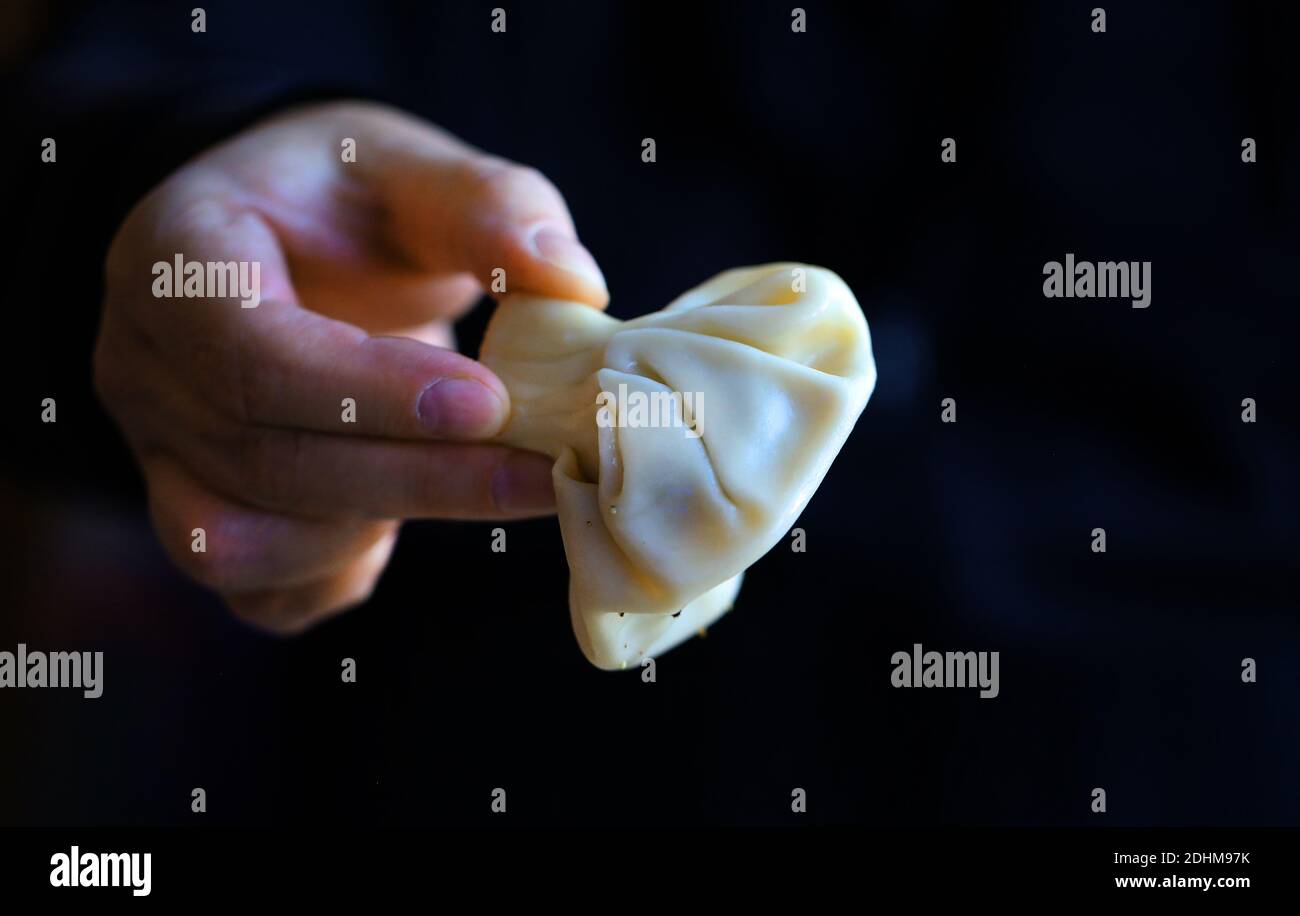 Foto einer Hand, die einen Knödel auf einem dunklen hält Hintergrund Stockfoto