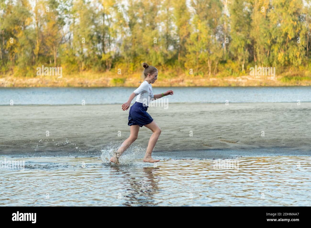 Ein Mädchen, das auf dem Wasser läuft. Das Mädchen spritzt Wasser. Fluss. Herbst. Stockfoto