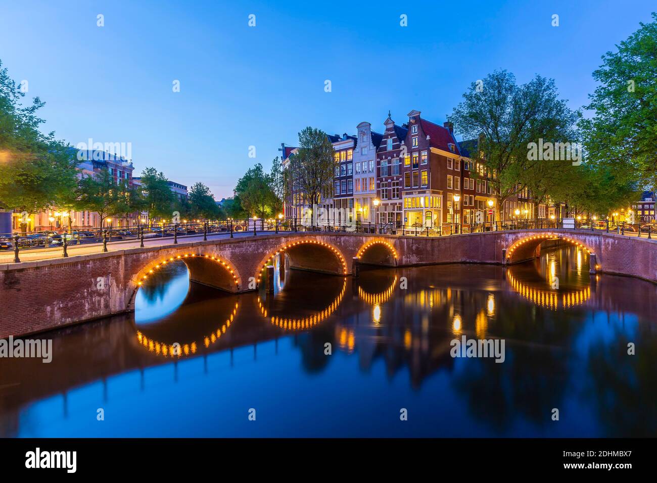 Amsterdamer Straßen und Kanäle in der Dämmerung. Brücken beleuchtet, Sommersaison. Beliebtes Reiseziel für Touristen. Stockfoto