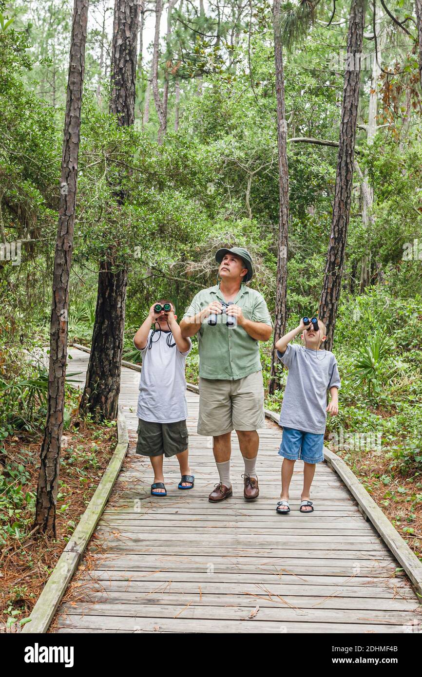 Alabama Dauphin Island Audubon Bird Sanctuary, Mann Großvater Enkel Söhne Junge Jungen Vogelbeobachter Ferngläser suchen, Naturlehrpfad Promenade, Stockfoto