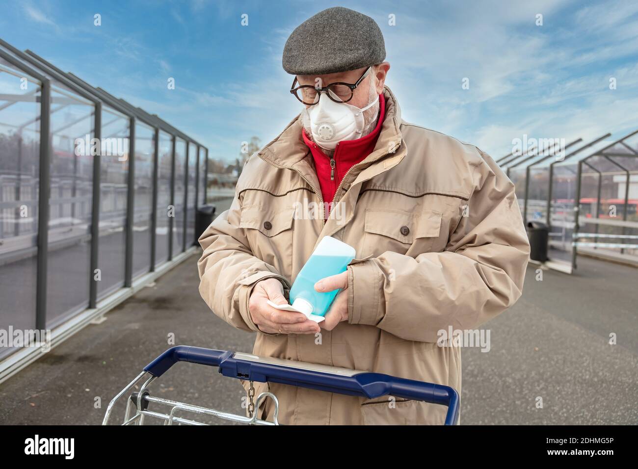 Mann mit Desinfektionsmittel in einer Plastikflasche und einem Einkauf Wagen Stockfoto