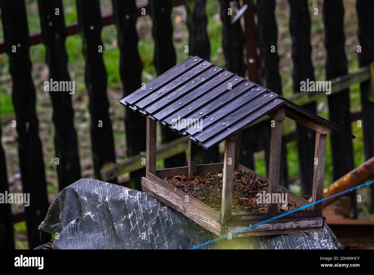 Vogelhaus mit schwarzen Fliesen auf einer grauen Folie Mit einem schwarzen  Zaun dahinter Stockfotografie - Alamy