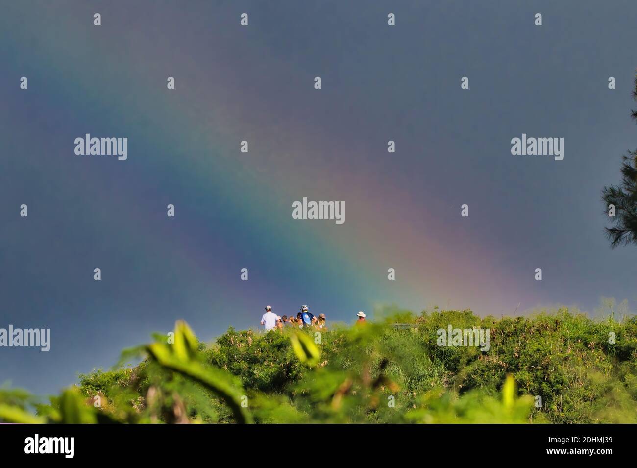 Nicht identifizierbare Menschen starren in den Raum unter einem brillanten Regenbogen. Stockfoto