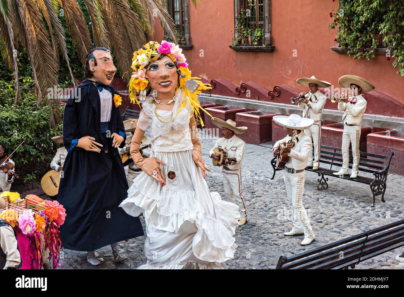 Eine traditionelle mexikanische Mariachi-Band spielt als riesige Puppen namens Mojigangas Tanz während einer Hochzeitsfeier im Lavaderos del Chorro Park in San Miguel de Allende, Guanajuato, Mexiko. Stockfoto