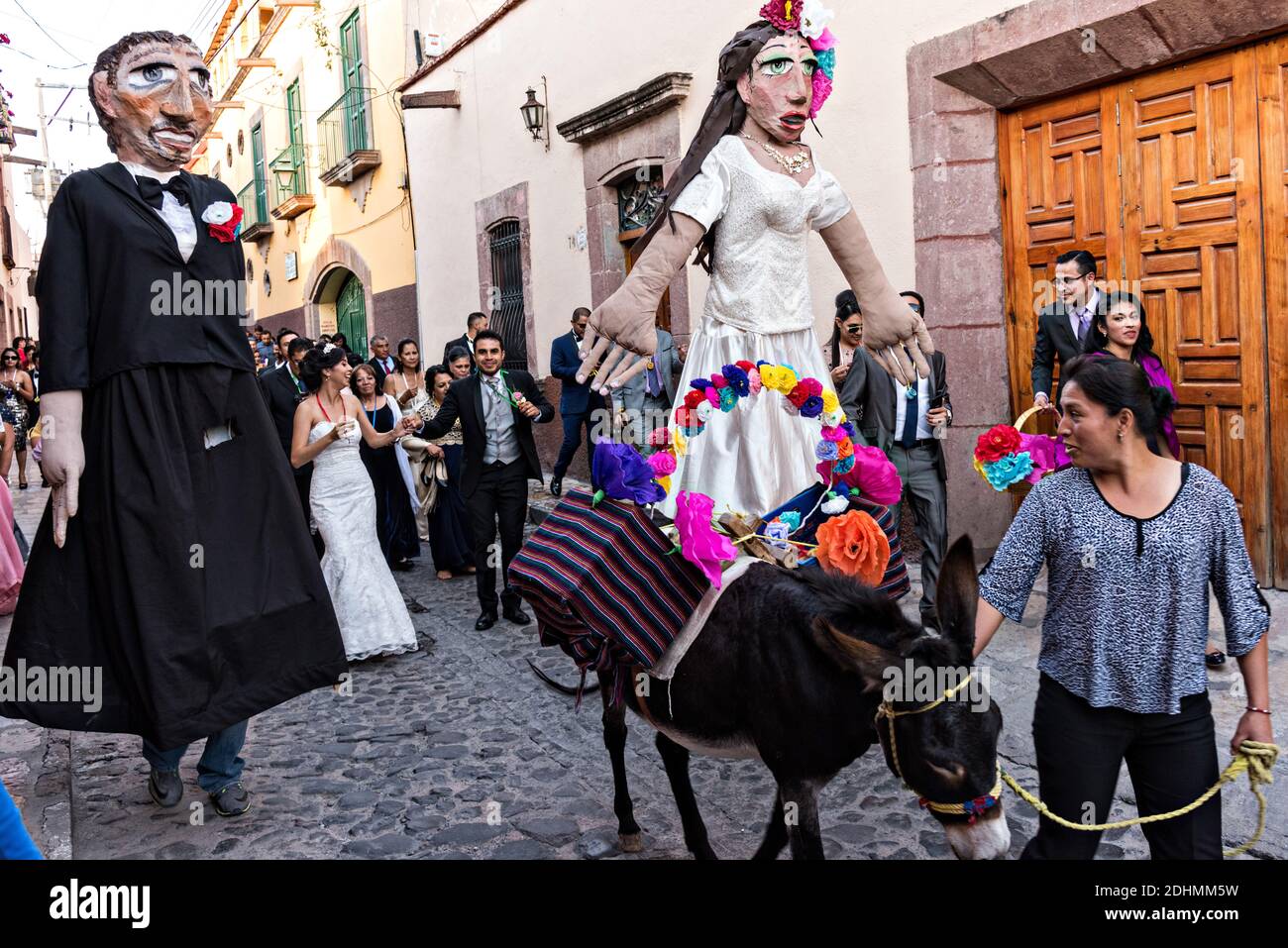 Ein geschmückter Esel führt den Weg als riesige Puppen genannt Mojigangas Tanz während einer Hochzeitsfeier Paraden durch die Straßen San Miguel de Allende, Guanajuato, Mexiko. Stockfoto