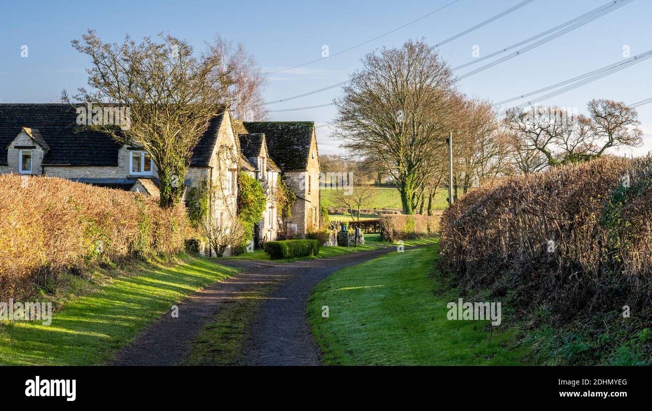 Traditionelle Hütten stehen auf einer grünen Gasse über Castle Combe in Englands Cotswolds. Stockfoto