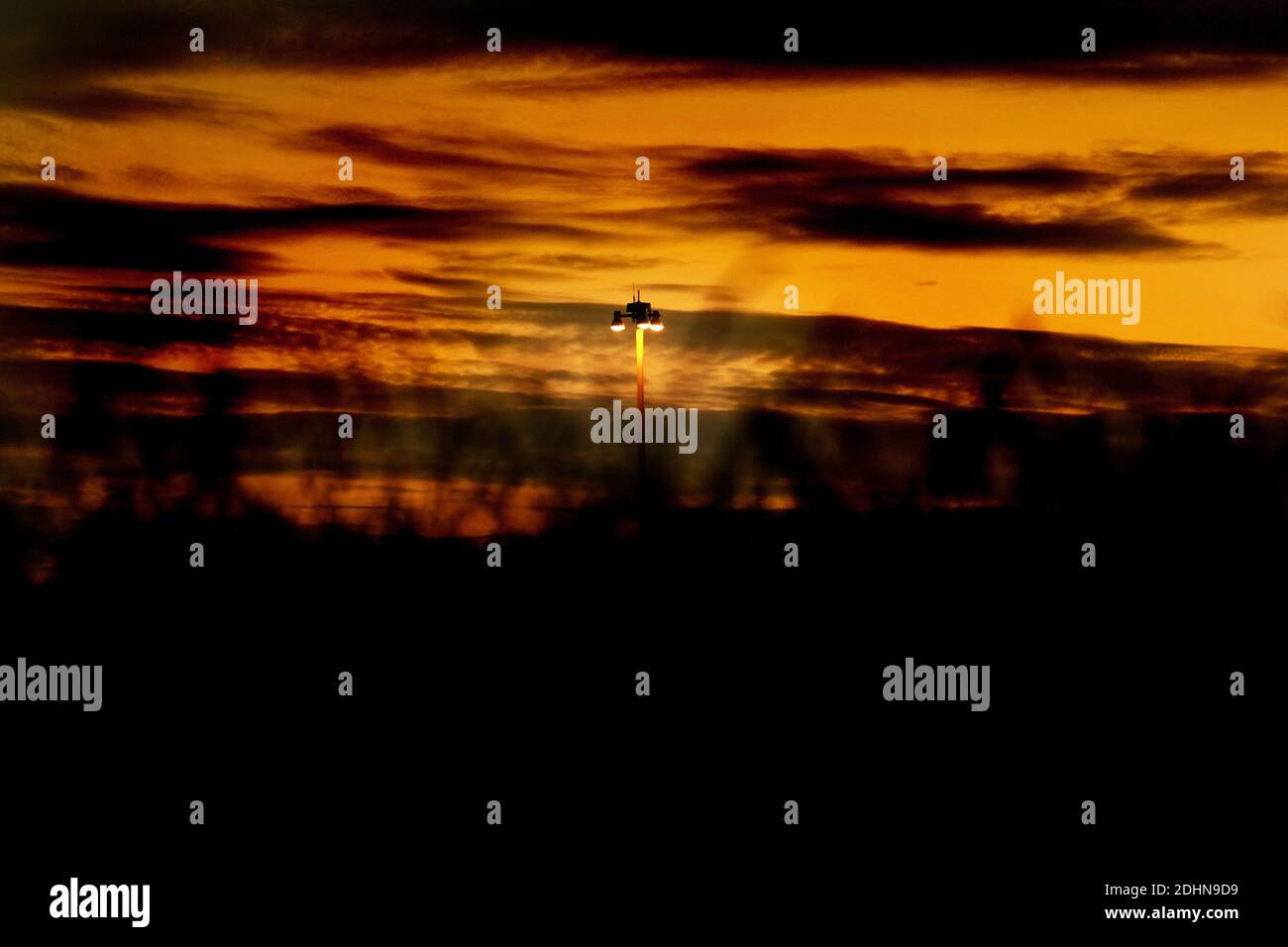 In der Abenddämmerung leuchtet eine Straßenlaterne auf. Stockfoto