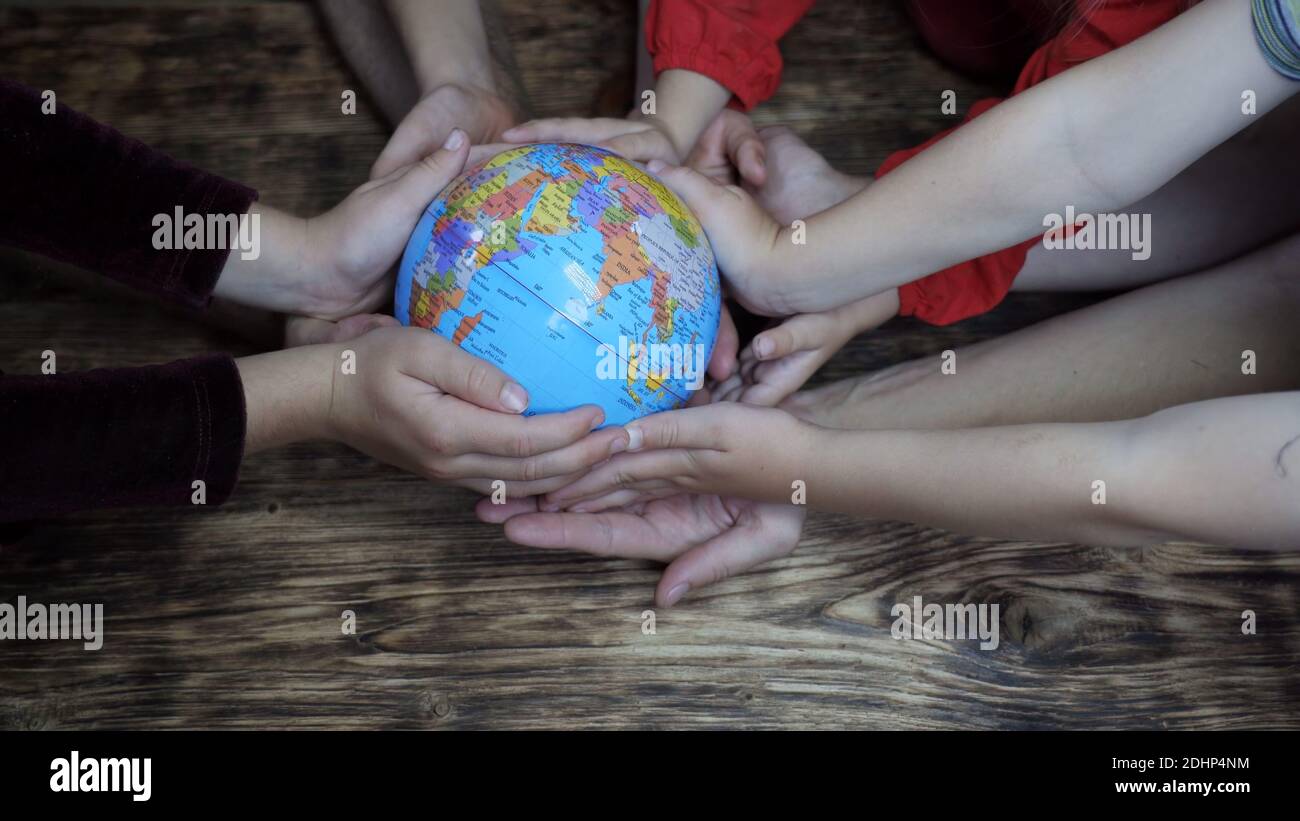 Eine freundliche Familie hält den Globus in ihren Händen. Das Konzept der Rettung der Welt. Stockfoto