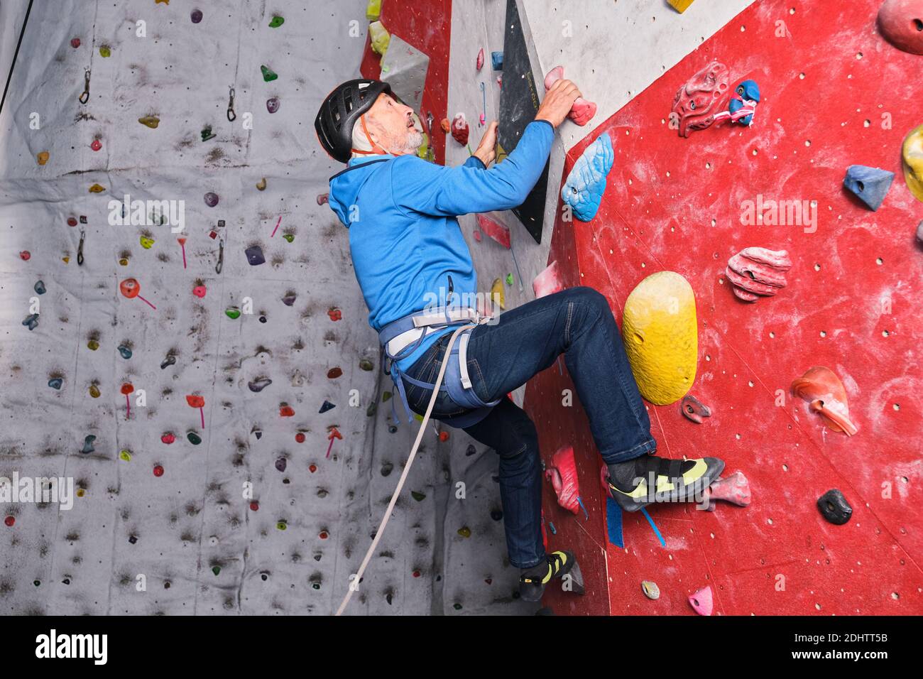 Professioneller Senior klettert auf einer künstlichen Kletterwand. Extremsportkonzept. Stockfoto