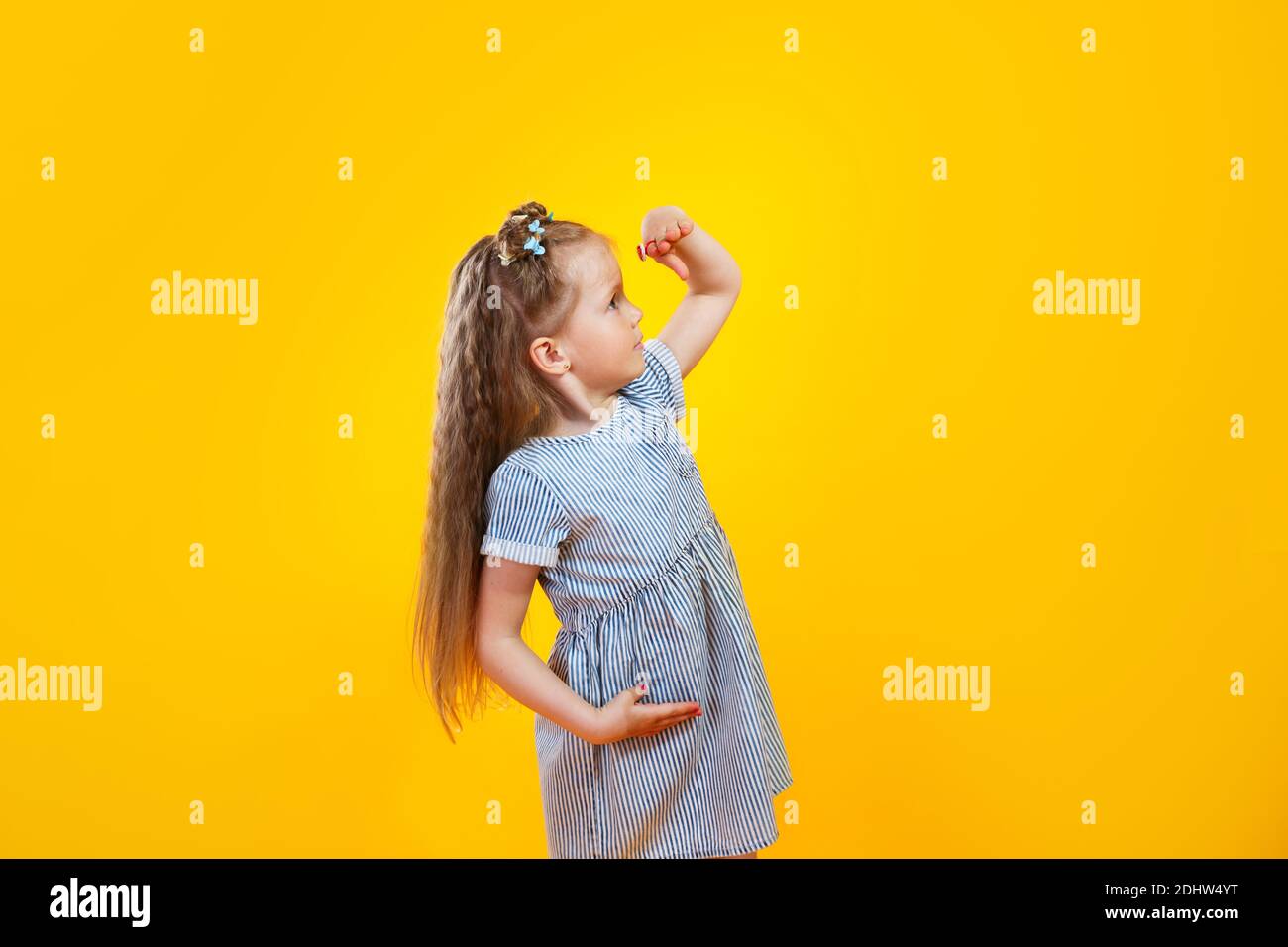 Lustige kleine Mädchen mit Blick nach vorne auf gelbem Hintergrund Stockfoto