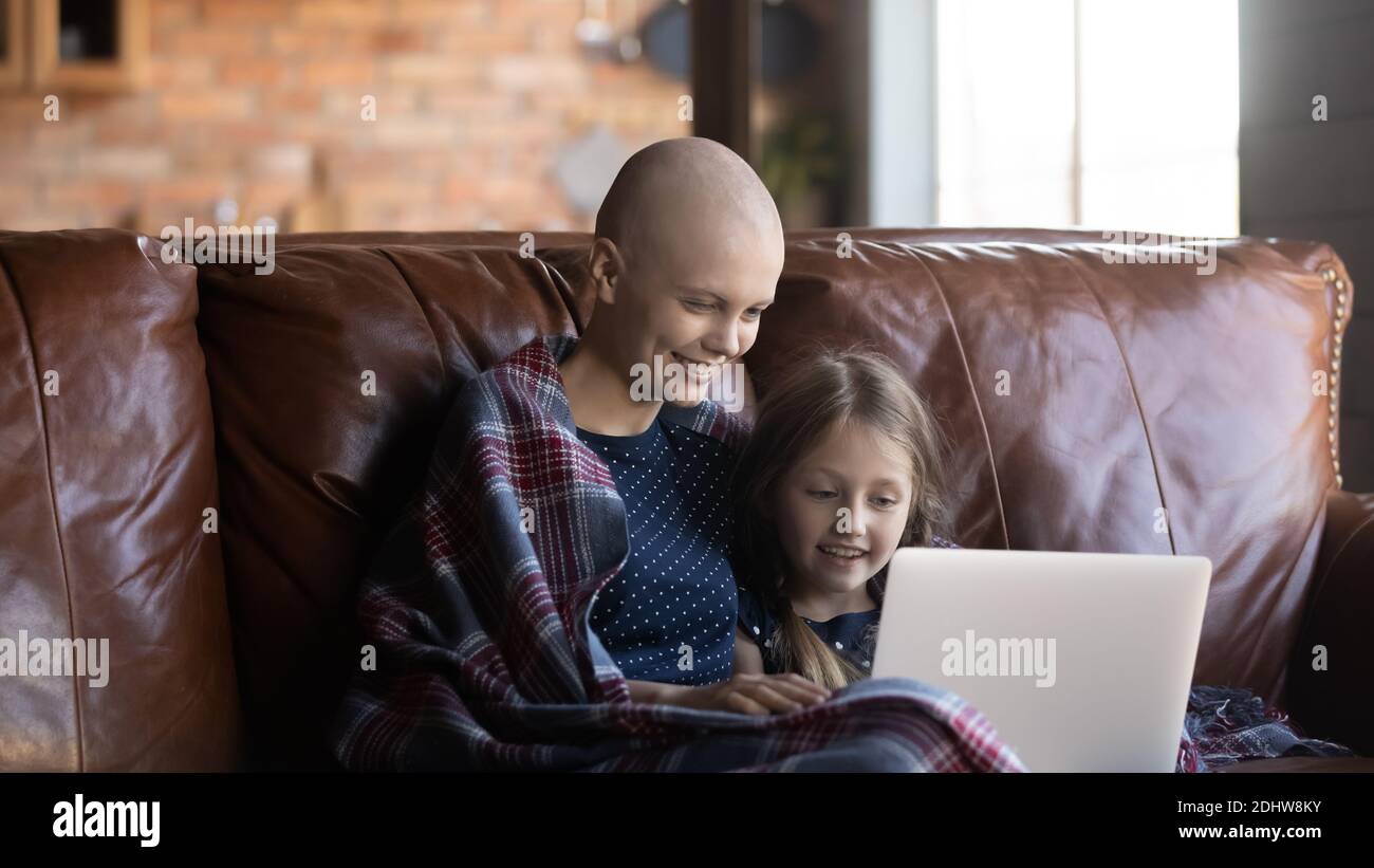 Glückliche haarlose Mutter mit kleinen Tochter mit Laptop, genießen Wochenende Stockfoto