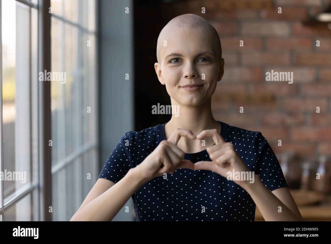 Kopf erschossen Porträt haarlos kranke Frau zeigt Herz-Geste Stockfoto