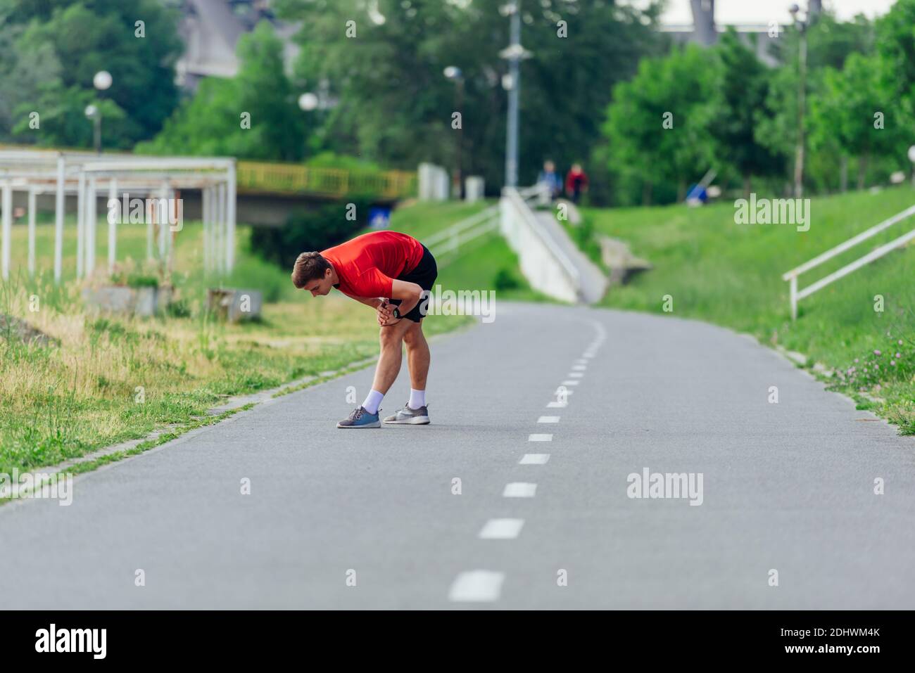Schöner junger Mann, der sich vor dem morgendlichen Training im Park dehnt und sich aufwärmt Stockfoto
