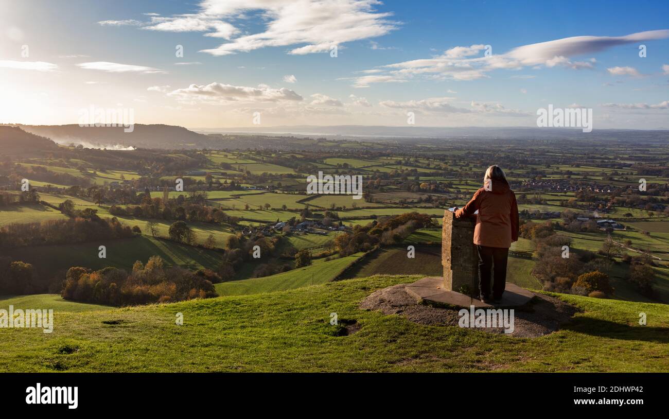Frau, die die Aussicht vom Aussichtspunkt auf Coaley Peak, The Cotswolds, Gloucestershire, Großbritannien, bewundert Stockfoto