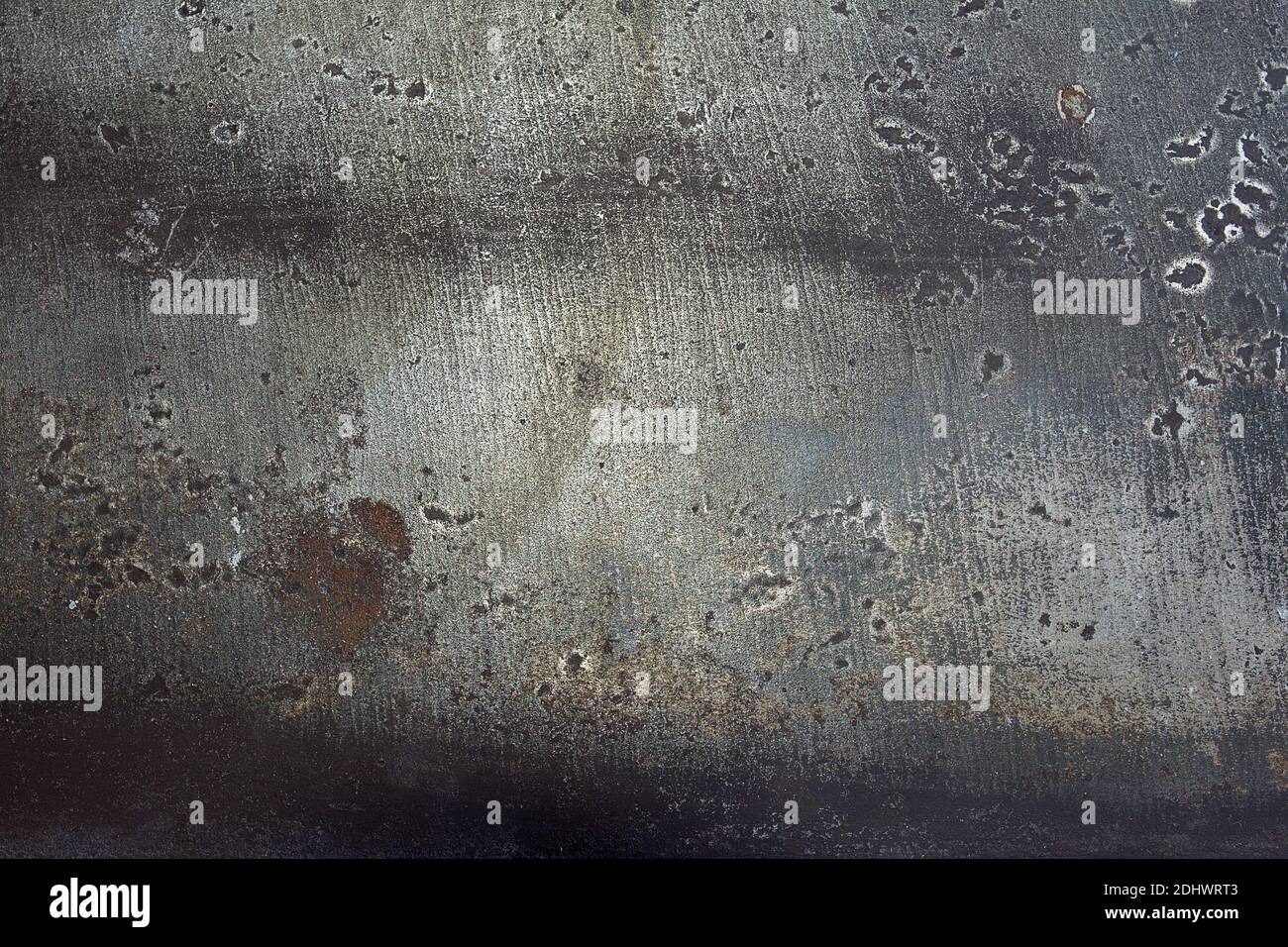 Abstrakte Landschaft aus abblätternder grauer Farbe auf einer Metallplatte. Rostige und verschmutzte Metalloberfläche mit Schweißbrennungen und Kratzern und Flecken. Künstlerische Textur. Stockfoto
