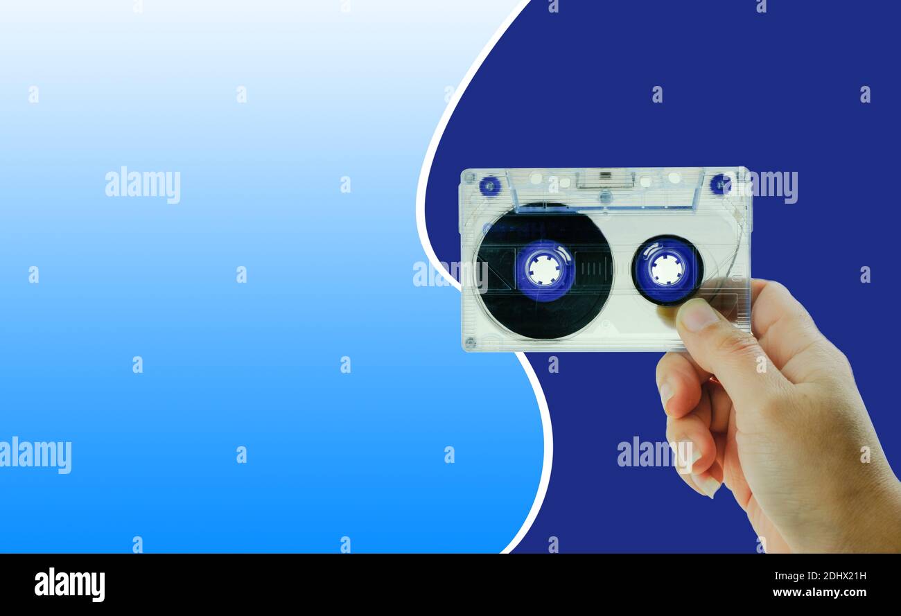 Frau Hand hält Kassette auf blauem Hintergrund Stockfoto