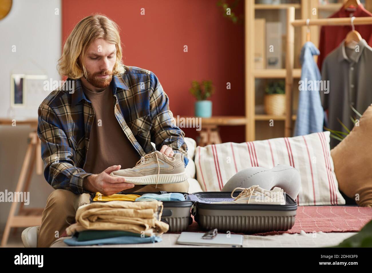 Junger Mann, der seine Kleidung in Koffer packt, geht er In den Urlaub Stockfoto