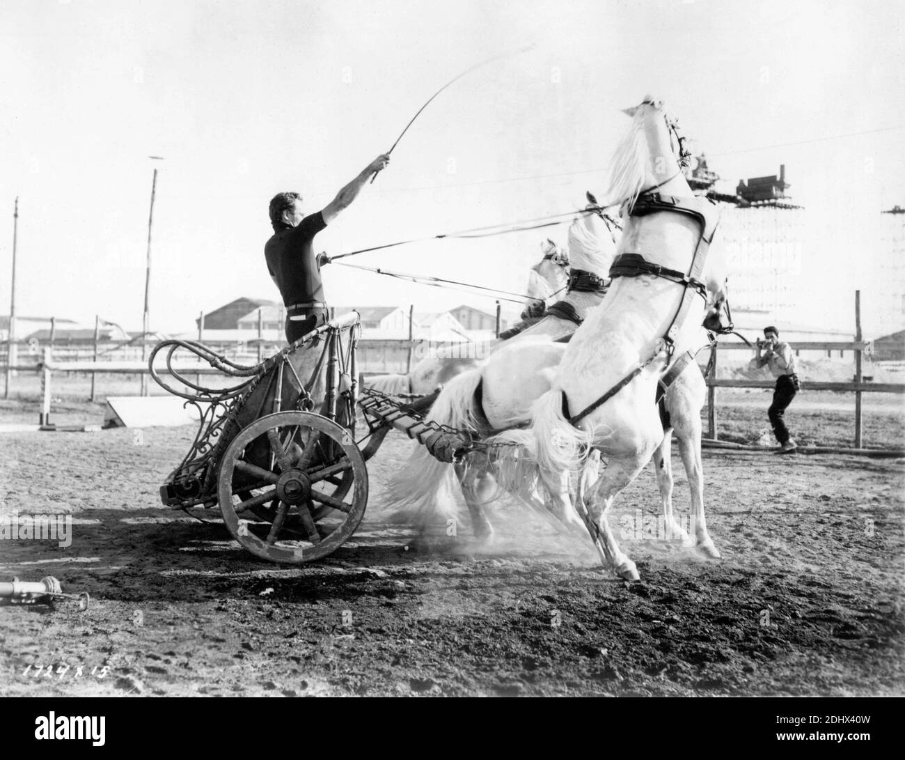 CHARLTON HESTON am Set Candid in den Cinecitta Studios in Rom Üben Fahrwagen mit italienischen Pressefotografen PIERLUIGI PRATURLON in Hintergrund fotografieren während der Dreharbeiten von BEN-HUR 1959 Regisseur WILLIAM WYLER Roman General Lew Wallace Drehbuch Karl Tunberg Musik Miklos Rozsa Kostümbild Elizabeth Haffenden Produzent Sam Zimbalist Metro Goldwyn Mayer Stockfoto