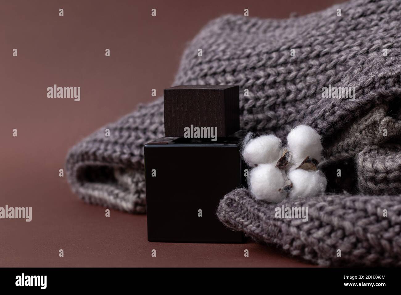 Parfüm, Herrenparfüm oder Lation After Shave auf einem braunen Hintergrund neben einem Herrenpullover und einem Baumwollball, Luxus, Geschenk. Nahaufnahme Foto für Stockfoto