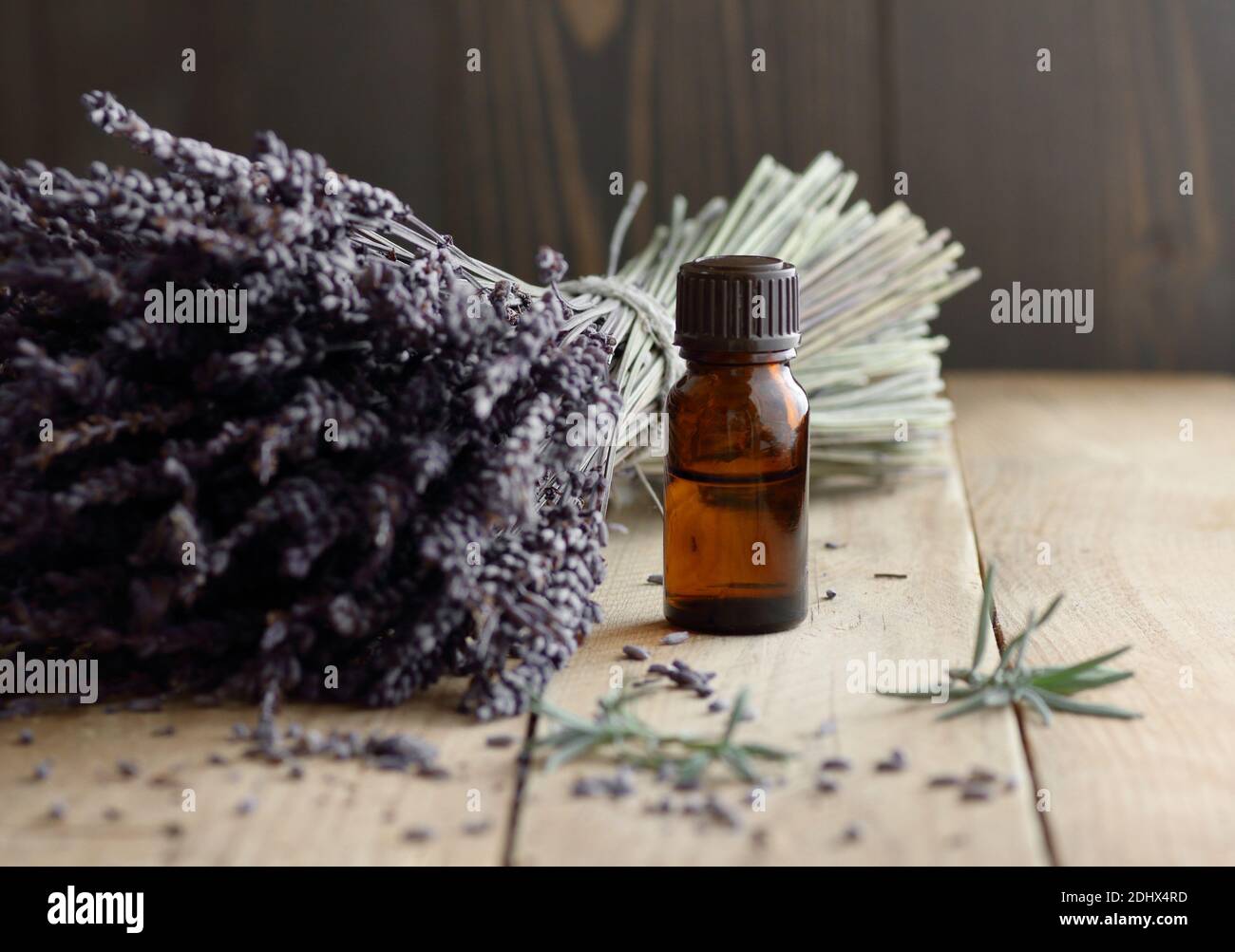 Lavendel ätherisches Öl in der Flasche mit Lavendelbukett und Kräuterblättern in der Nähe auf rustikalem Holztisch, Nahaufnahme, Kopierraum, Naturkosmetik, arom Stockfoto