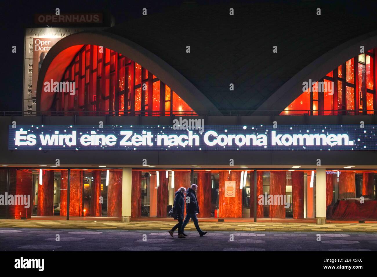 Dortmund, 11. Dezember 2020: Das Dortmunder Theater, das wegen der Koronakrise geschlossen wurde, leuchtet in roten Farben. Der Text DORT WIRD EINE ZEIT KOMMEN, NACHDEM CORONA auf die Vorbuchung für die Saison 2021 verweist Stockfoto