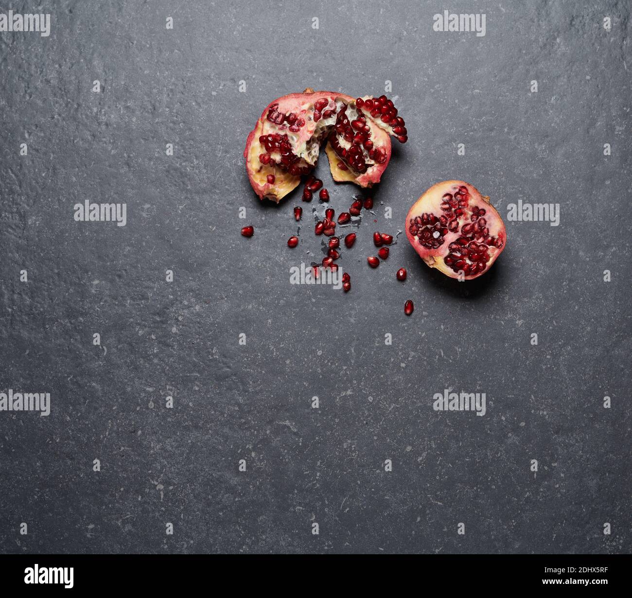Bunte Granatapfel isoliert auf dunkelgrauem Stein Hintergrund. Draufsicht. Gesunde und frische Früchte zur Steigerung von Vitamin C und Immunsystem, Draufsicht. Stockfoto