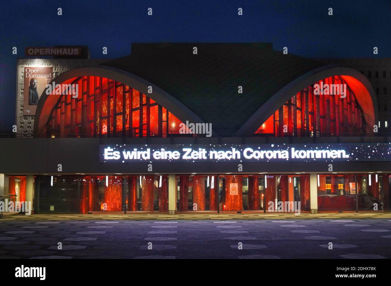 Dortmund, 11. Dezember 2020: Das Dortmunder Theater, das wegen der Koronakrise geschlossen wurde, leuchtet in roten Farben. Der Text DORT WIRD EINE ZEIT KOMMEN, NACHDEM CORONA auf die Vorbuchung für die Saison 2021 verweist Stockfoto
