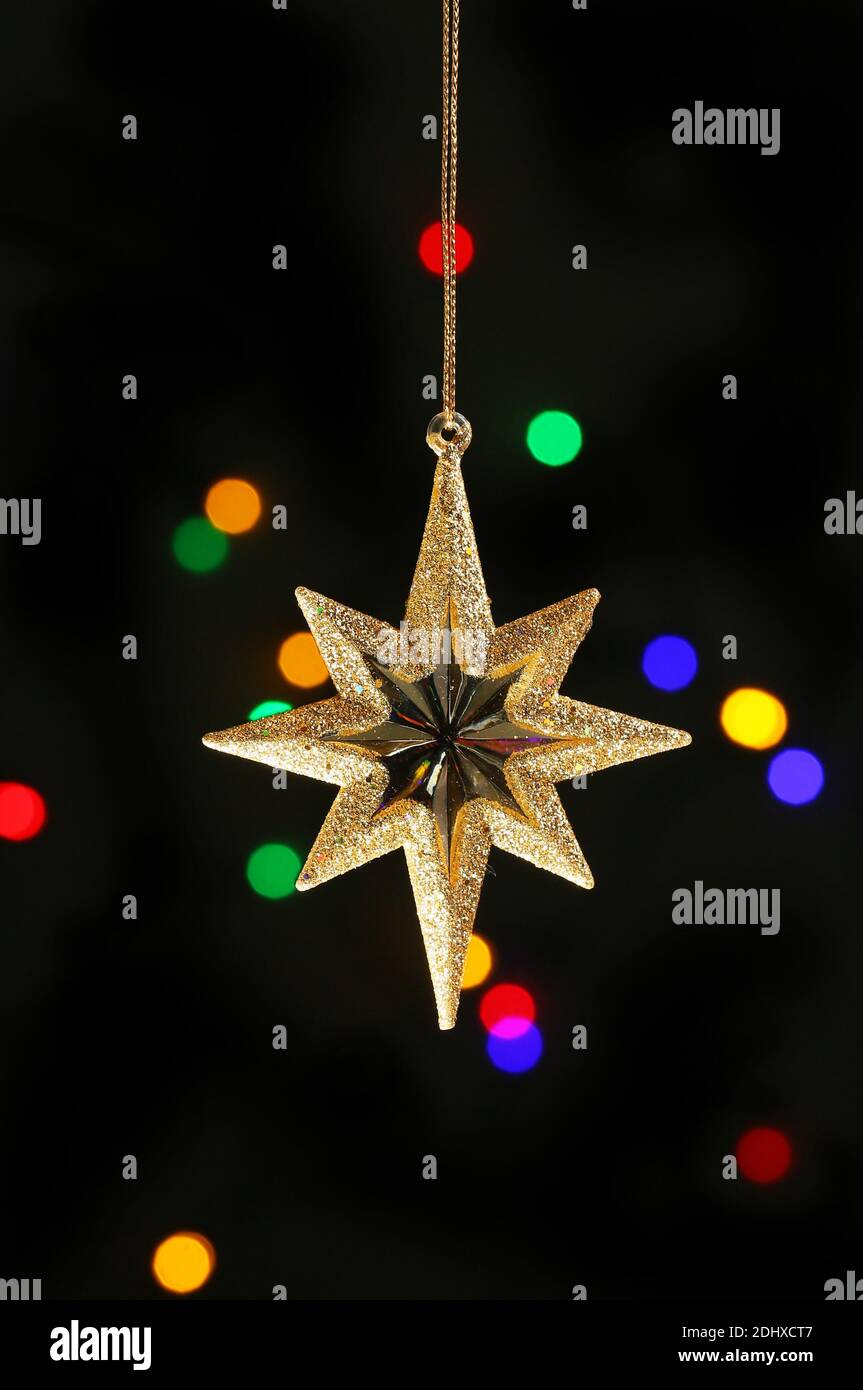 Gold Glitzer Weihnachtsstern Ornament vor einem Bokeh hellen Hintergrund Stockfoto