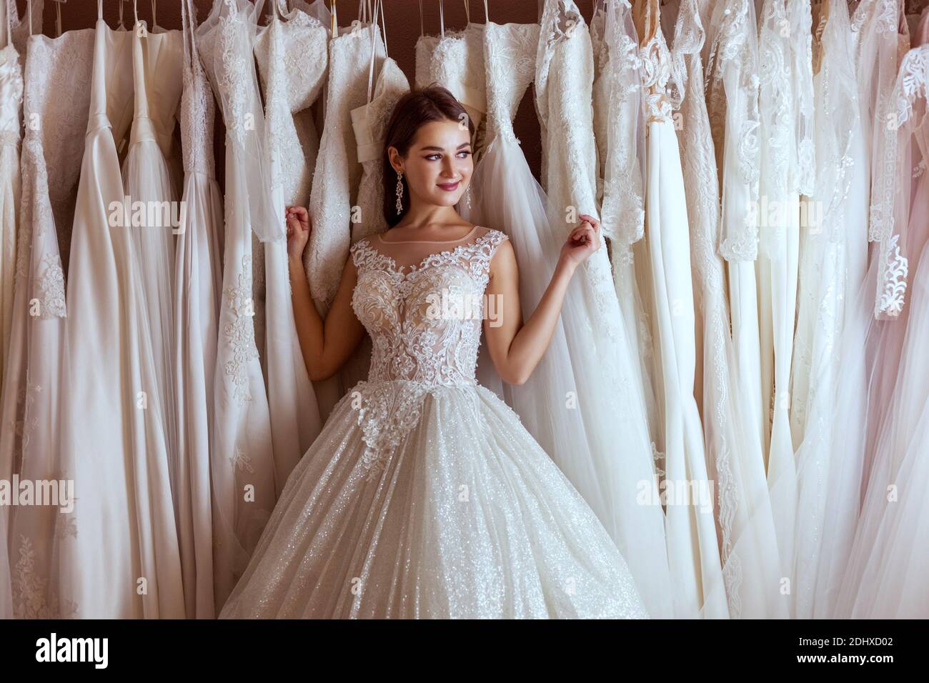 Junge schöne Frau in einem Hochzeitskleid unter den Satz von teuren Brautkleider. Stockfoto