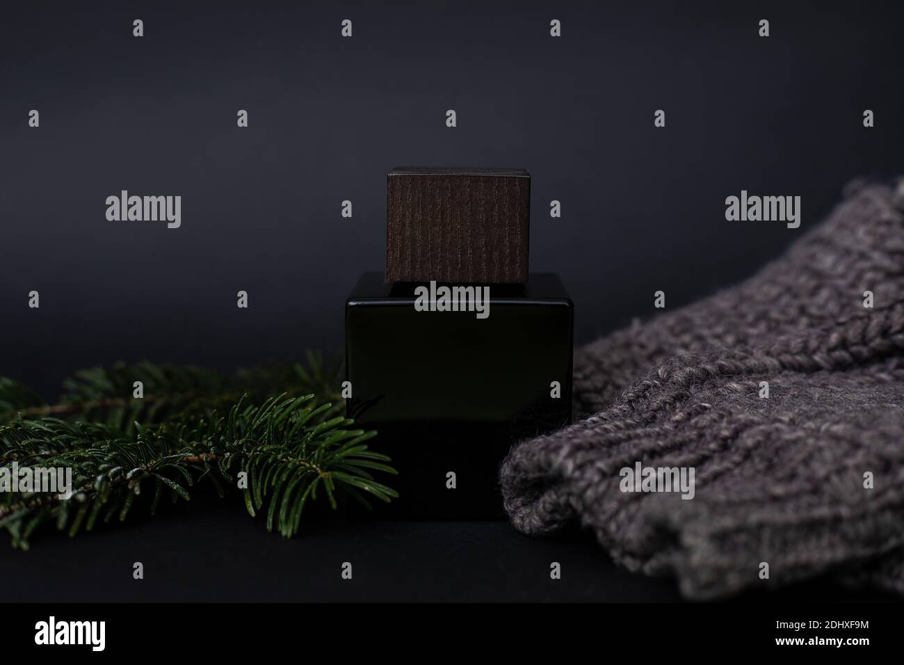 Parfüm, Herrenparfüm oder Lation nach der Rasur auf einem schwarzen neben einem Herrenpullover und Nadeln, Fichte. Luxus, Geschenk. Nahaufnahme Foto für Werbung ein Stockfoto