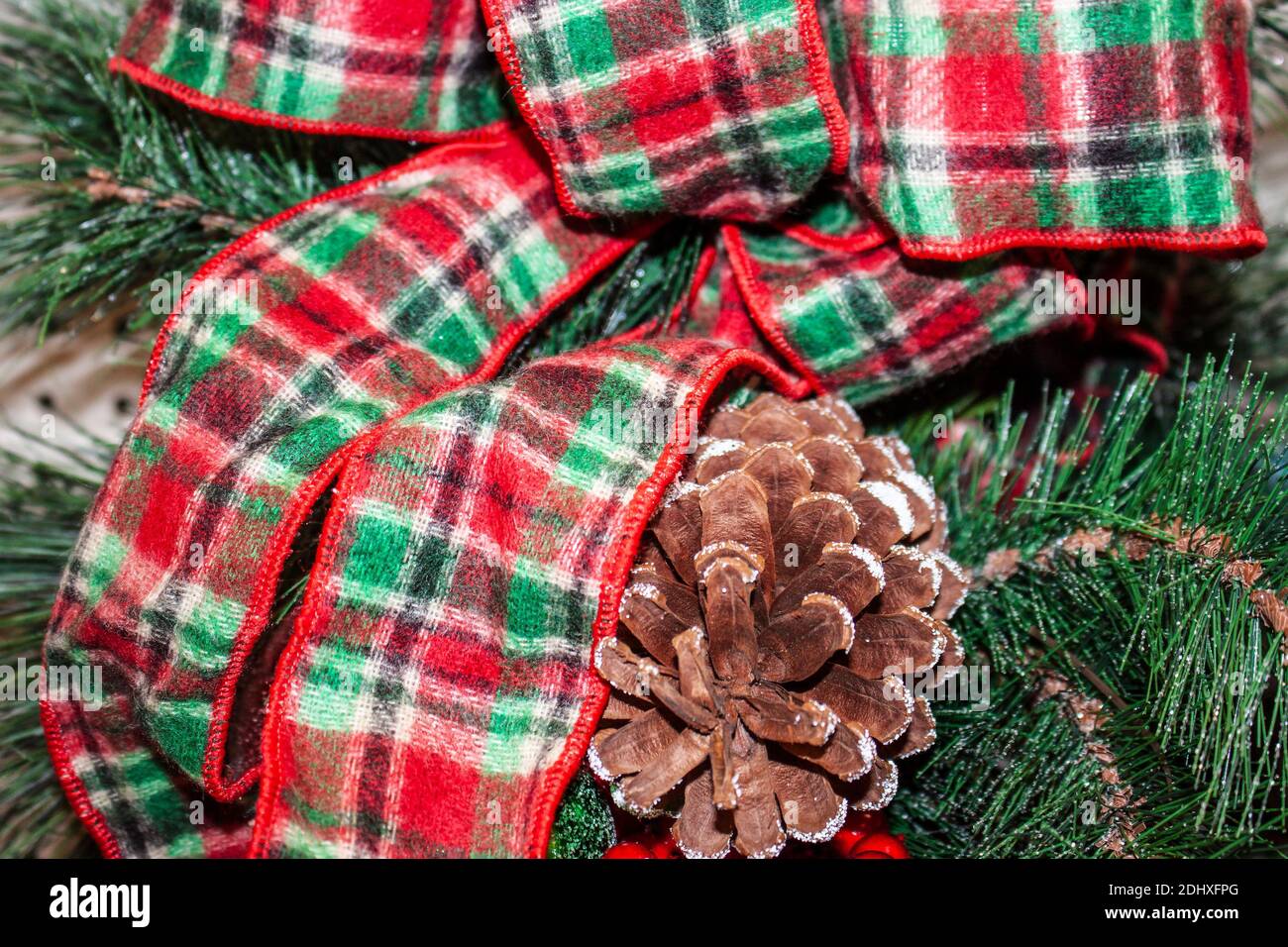 Weihnachten Hintergrund - verschneite Kiefer Kegel mit Fuzzy karierten Band Bogen und Grün - selektiver Fokus Stockfoto