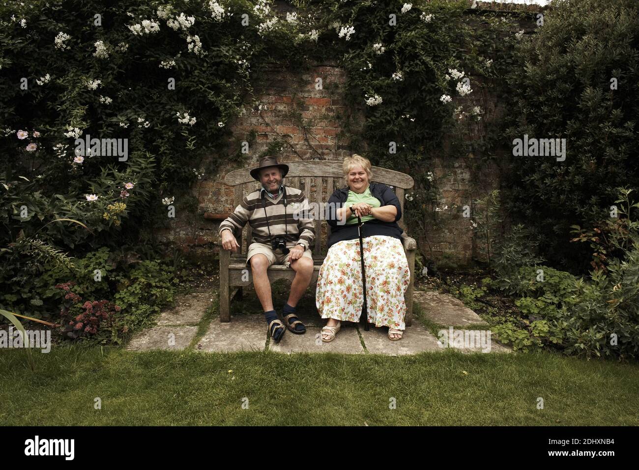 Reifes englisches Paar, das auf einer Bank sitzt und den Garten im Antony House, Torpoint, Cornwall, Großbritannien, genießt. Stockfoto