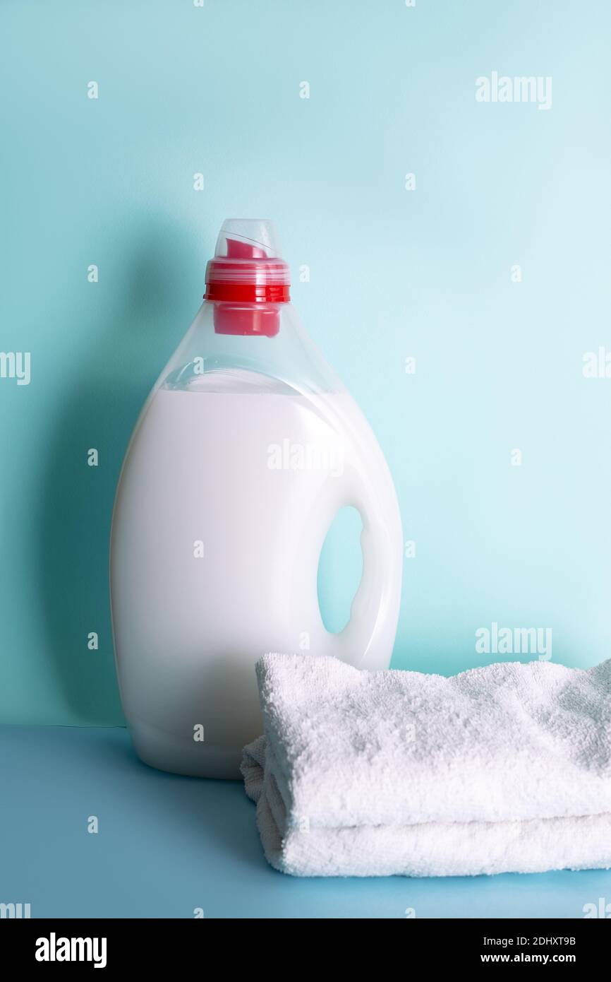 Waschmittel in der Flasche mit Flüssigkeit und Handtücher auf blauem Hintergrund. Wasch- oder Bleaching-Konzept Stockfoto