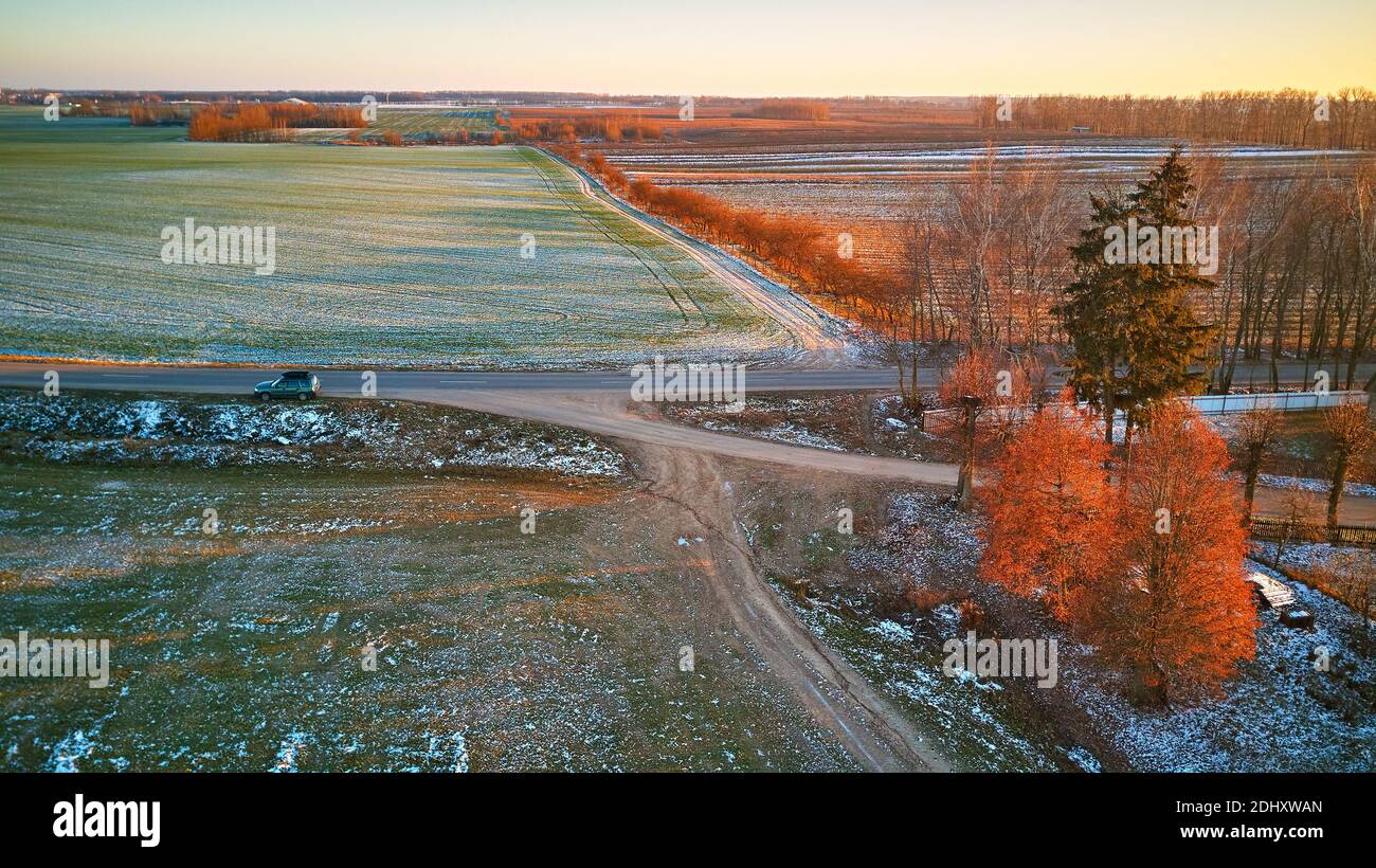 Winter grün Agrarfeld Winterpflanzen unter Schnee. Bunte Bäume Dezember Sonnenuntergang Luftbild. Landstraße. Blick auf die Landschaft von oben. Minsk-Reg Stockfoto