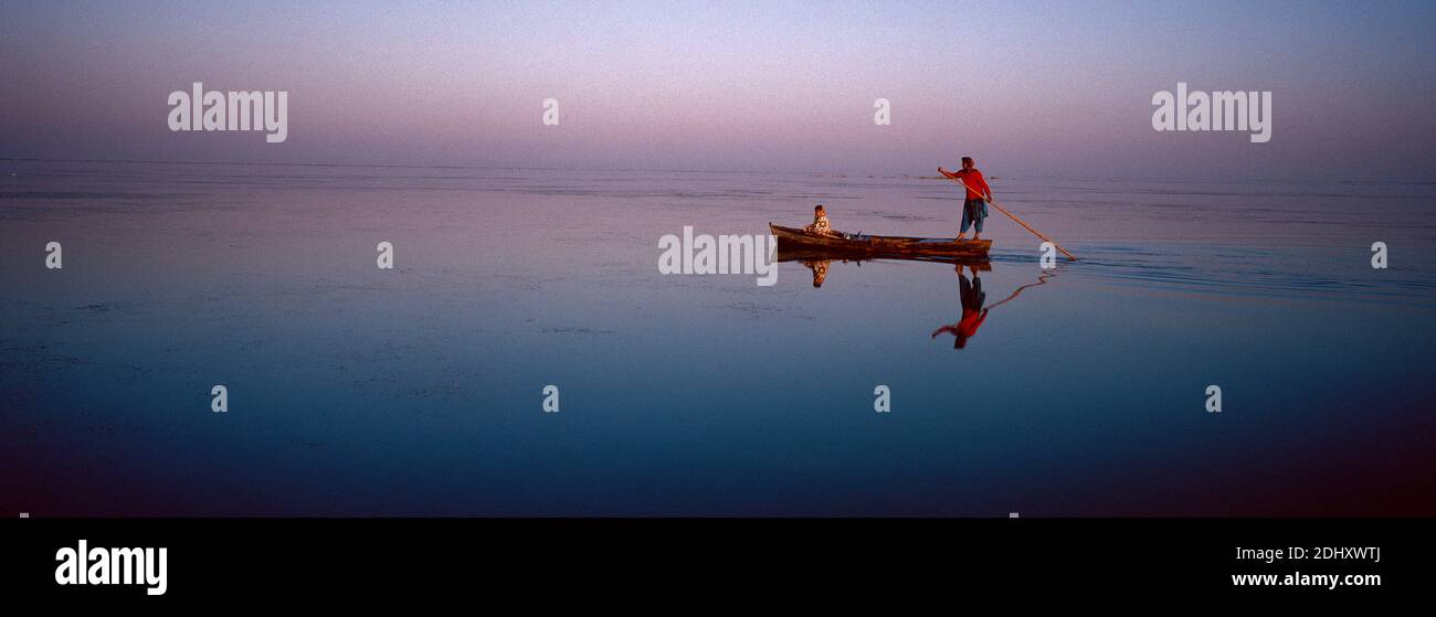 Zwei Peopel auf einem alten hölzernen Boot beobachten den Sonnenaufgang Manchhar See in Pakistan. Stockfoto