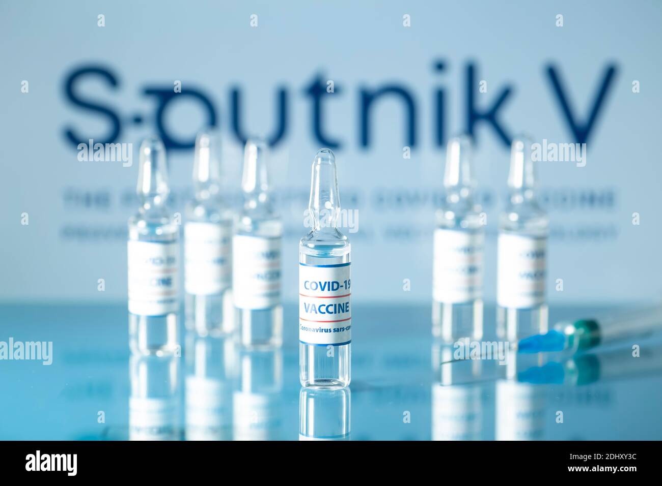 Sputnik 5 Impfstoff gegen COVID-19 Konzept. Medizinische Glasfläschchen mit Flüssigkeit auf dem Hintergrund Sputnik V Firmenlogo. Ampullen mit Coronavirus Vaccin Stockfoto