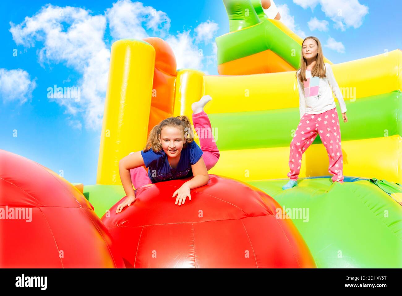 Glückliche kleine Mädchen haben viel Spaß beim Springen von Ball zu Ball auf einem Schloss aufpumpen. Stockfoto