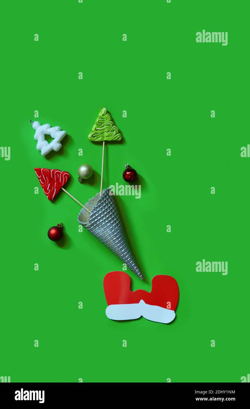 Weihnachten Komposition. Eis mit Baum von Kugeln, Zuckerstangen und Süßigkeiten auf grünem Hintergrund. Weihnachten, Winter, neues Jahr. Flach, Stockfoto