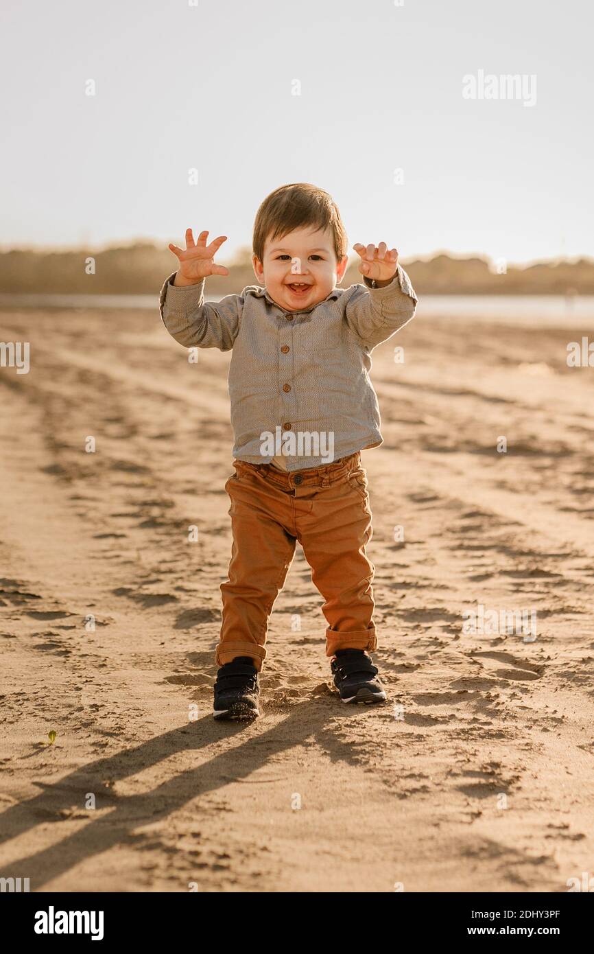 Niedliches Kleinkind Baby Junge zu Fuß auf dem Sandstrand. Stockfoto