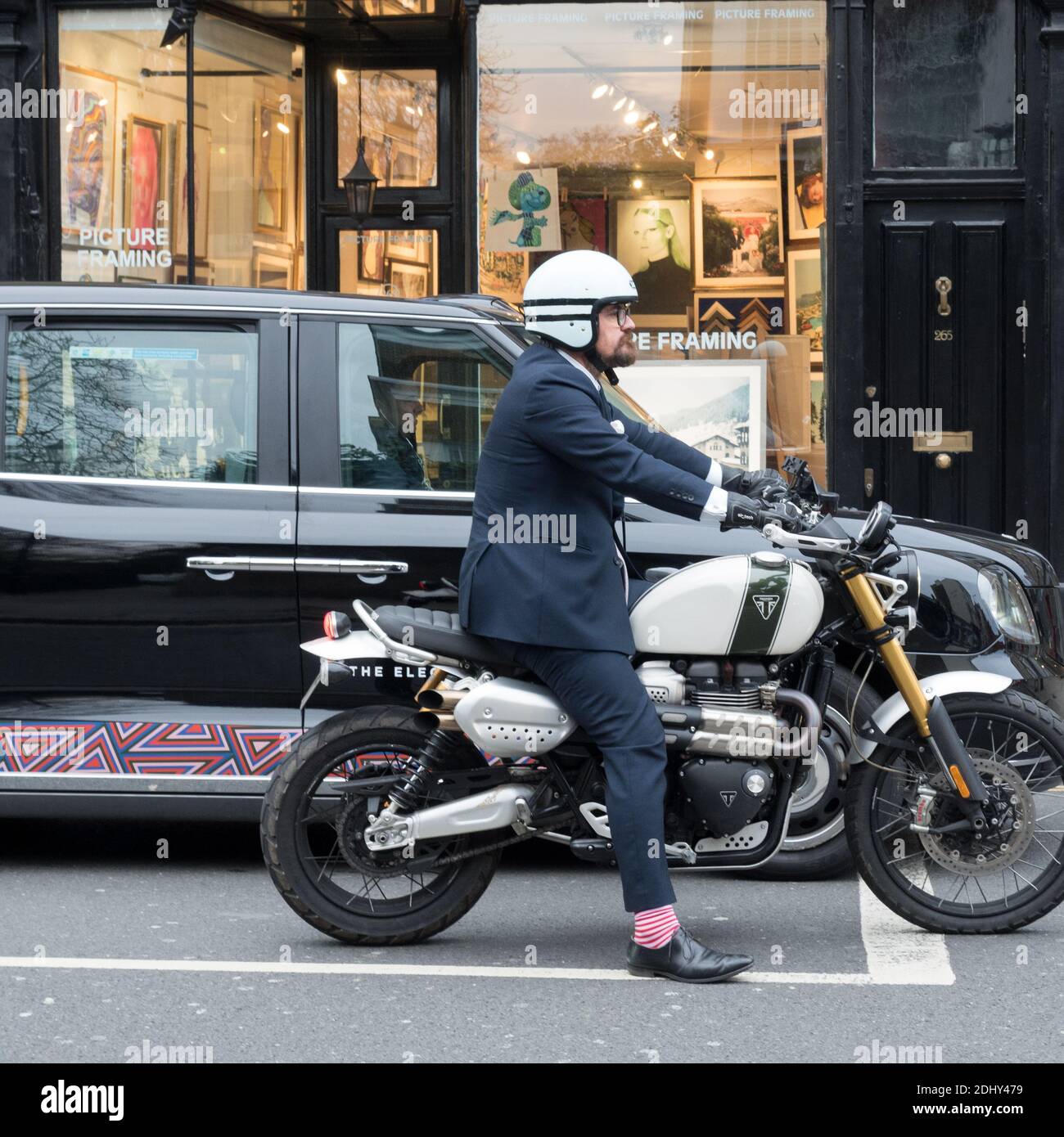 London, Greater London, England - Motorradfahrer mit bunten Socken passend Taxis Rockfarbe Stockfoto