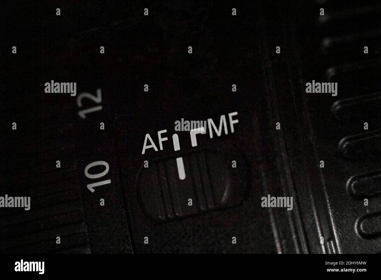 Nahaufnahme des AF MF-Schalters am Kameraobjektiv. Schieberegler zum Ändern des Autofokus-Modus. Dunkler Hintergrund. Stockfoto